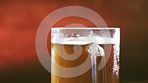 A frothing cold light beer in a glass mug rotates in a circle.