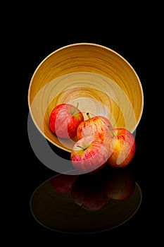 Frour ripe sweet red apples in a bamboo container on dark background