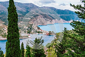 Frourio peninsular and Assos village with beautiful sea bay and cypress trees in foreground. Kefalonia island, Greece