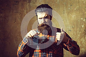 Frown bearded man holding set of wrenches with thumbs up