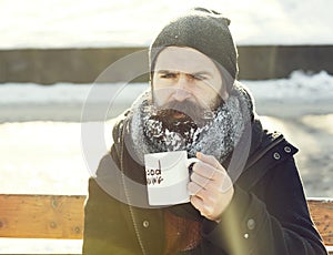 Frown man, bearded hipster with beard and moustache covered with white frost drinks from cup with good morning text