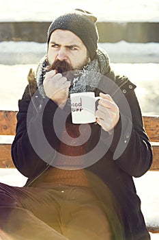 Frown man, bearded hipster with beard and moustache covered with white frost drinks from cup with good morning text