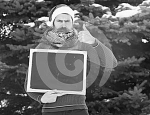 Frown santa with blank chalkboard on natural background, copy space