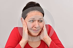 Frowning beautiful woman covering her ears with hands