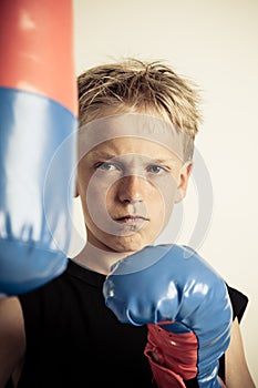 Frowning boy wearing black shirt and boxing gloves