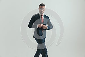 Frowning businessman with eyeglasses unbuttoning suit and walking