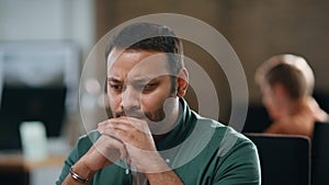 Frowning man sitting office thinking at work close up. Thoughtful businessman