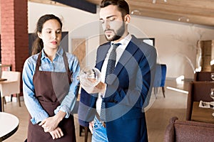 Frowning restaurateur checking wineglass