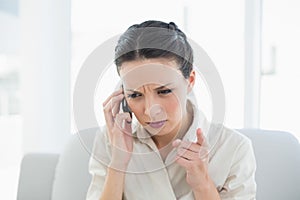 Frowning stylish brunette businesswoman making a phone call