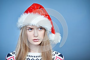 Frowning worried woman wearing Santa hat looking aside