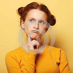 Frowning young woman thinking on yellow background