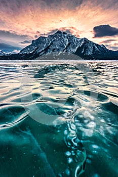 Frozen Abraham Lake with rocky mountains and natural bubbles frost in the morning on winter at Banff national park