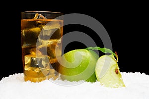 Frozen apple juice,ice cubes and apple with leaves on black on snow