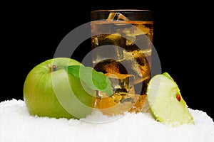 Frozen apple juice,ice cubes and apple with leaves on black on snow