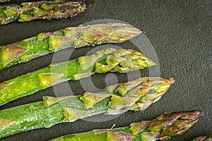 Frozen asparagus stems on dark background closeup