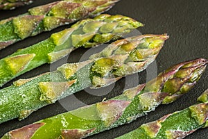 Frozen asparagus stems on dark background closeup