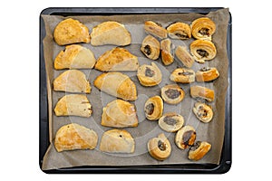 Frozen baked patties and dumplings in dough on a baking sheet on baking paper, isolated on a white background with a clipping path