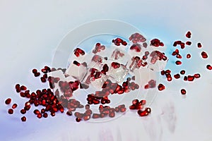 Frozen berries, Ice cubes and pomegranate granules scattered on a grey background