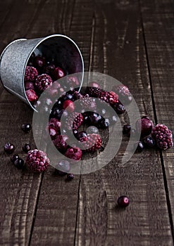 Frozen berries mix in a black bowl on wooden background