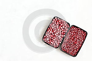 Frozen berries in plastic containers on a white background. Storage of frozen food. Cranberries and cowberries. Copy space, top