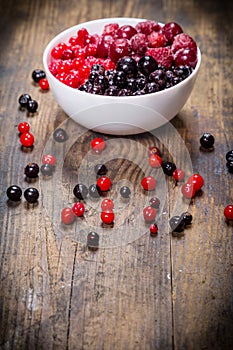 Frozen berries in plate on wooden background