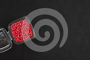 Frozen berries in a transparent container on a black background. Frozen red currant. Copy space, top view, flat lay