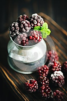 Frozen blackberries on a wooden table. Vertical.