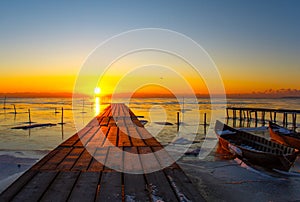 frozen boat in winter on the lake at sunrise