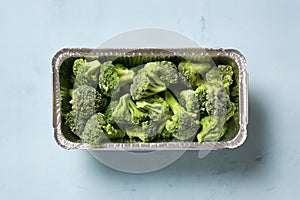 Frozen broccoli on a blue surface, flat lay