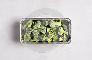 Frozen broccoli cabbage on gray surface, flat lay, healthy food concept.