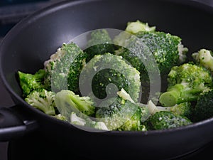 Frozen broccoli cooking in a frying pan