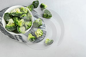 Frozen broccoli florets on light grey table. Vegetable preservation