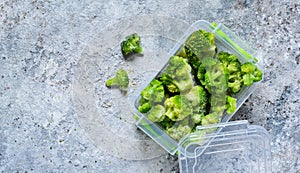 Frozen broccoli in lunch box on a concrete background