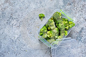 Frozen broccoli in lunch box on a concrete background with space for text