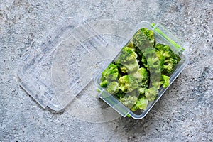 Frozen broccoli in lunch box on a concrete background with space for text