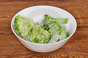 Frozen broccoli in white bowl on the rustic table photo