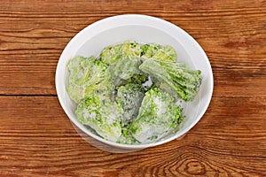 Frozen broccoli in white bowl on the rustic table photo