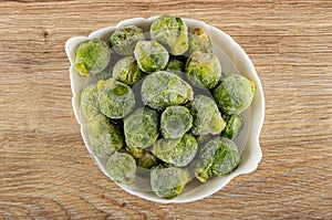 Frozen broccoli in white bowl on table. Top view