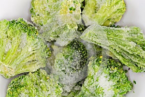 Frozen broccoli in white bowl, top view close-up photo