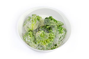 Frozen broccoli in white bowl on a white background