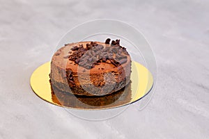 Frozen cake, chocolate cheesecake on a golden backing. Grey background, selective focus, copy space