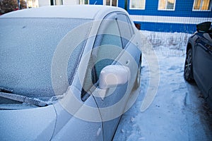 Frozen car, car windshield, glass covered with ice crusts, front view, snow, ice,