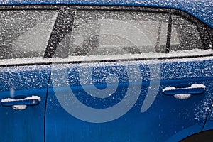 Frozen car windshield covered with ice and snow on a winter day.