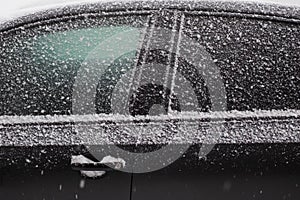 Frozen car windshield covered with ice and snow on a winter day.