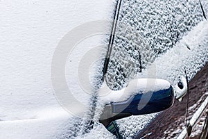 Frozen car windshield covered and rearview mirror with ice and snow on a winter day