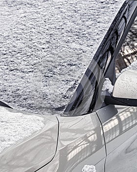 Frozen car windshield covered and rearview mirror with ice and snow on a winter day