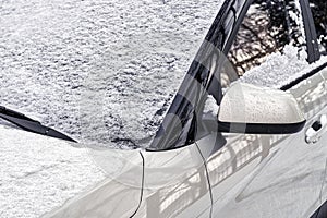 Frozen car windshield covered and rearview mirror with ice and snow on a winter day