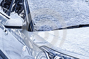 Frozen car windshield covered and rearview mirror with ice and snow on a winter day.