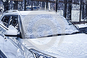 Frozen car windshield covered and rearview mirror with ice and snow on a winter day.