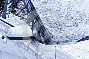 Frozen car windshield covered and rearview mirror with ice and snow on a winter day.